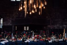 a long table covered in lots of flowers and lights hanging from it's ceiling