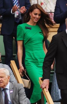 a woman in a green dress is walking down the steps with an older man behind her