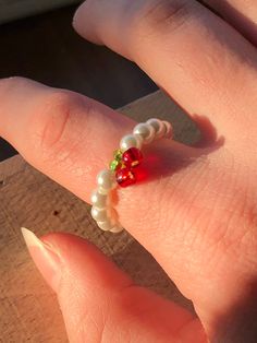 a person's hand with a ring made out of pearls and glass beads on it