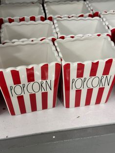 red and white striped popcorn cups with the word popcorn written on them