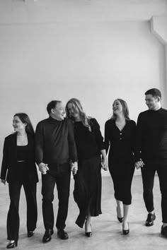 a group of people standing next to each other in front of a white wall with windows