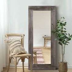 a room with a chair, mirror and potted plant