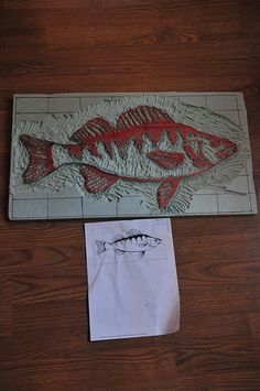 a fish is on the floor next to a piece of paper