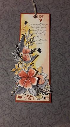 a card with flowers on it hanging from a string in front of a gray wall