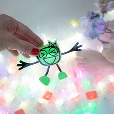 two hands reaching for an ornament made out of plastic bottles with lights in the background