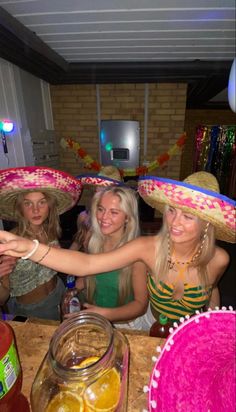 three women wearing sombreros and hats at a party