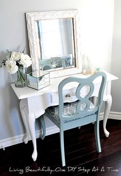 a blue chair sitting next to a white desk with a mirror on top of it