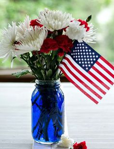 an american flag and flowers in a blue mason jar