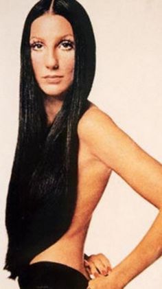 a woman with long black hair and no shirt is posing for the camera, her hands on her hips