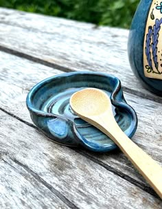 a wooden spoon sitting on top of a blue bowl next to a vase with flowers