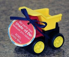 a yellow and red toy truck with a blue ribbon around it's neck on a gray surface