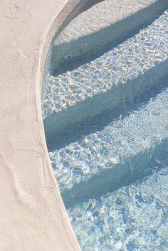 an empty swimming pool with blue water and white steps leading up to the bottom floor