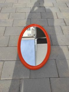 a person standing in front of a mirror on the ground next to a red object