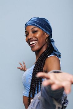 a woman in a blue shirt is holding her hand out to the side and smiling