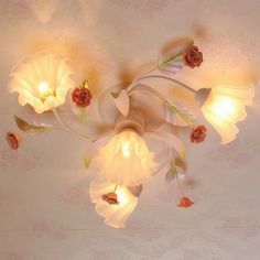 a chandelier that has flowers on it and lights hanging from the ceiling above