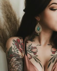 a woman with tattoos on her chest and arm is looking down at the camera while wearing an earring