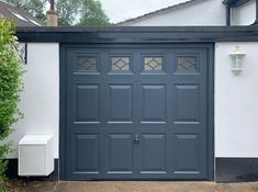 a grey garage door in front of a white house