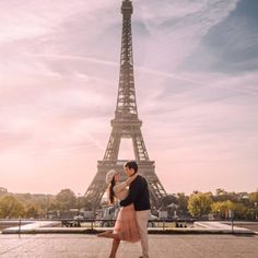 a man and woman are standing in front of the eiffel tower, paris