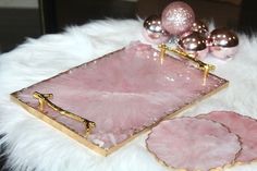 pink and gold serving trays sitting on a white fur covered table with christmas ornaments