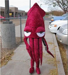 a person in an octopus costume is walking down the sidewalk next to a parking lot