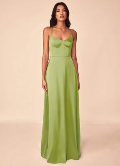 a woman in a long green dress with spaghetti top and low back, standing against a white background