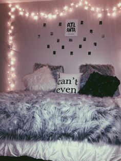 a bed that has some lights on the headboard and pillows in front of it