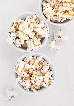 three bowls filled with popcorn and sprinkles on top of a white surface