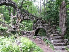 an old stone building in the woods with stairs leading up to it's entrance