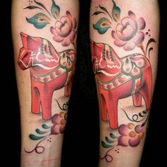 two tattoos on both legs with flowers and an elephant in the middle one is red