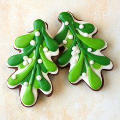 two decorated cookies with green and white icing on a marble surface, one is shaped like a christmas tree