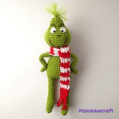 a crocheted green frog with a red and white striped scarf on it's back