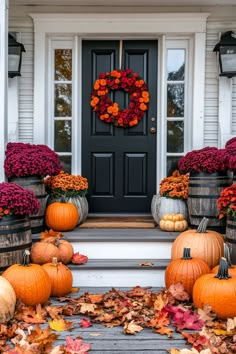 pumpkins and gourds on the front steps of a house with fall leaves