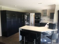 a modern kitchen with black cabinets and white counter tops is seen in this image from the living room