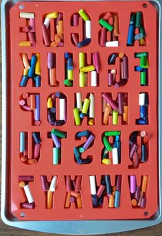 an alphabet made out of crayons sitting on top of a red plastic tray