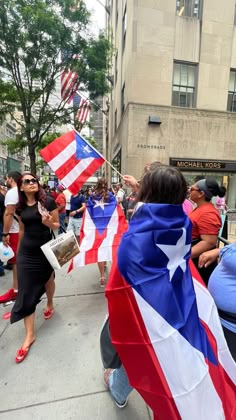 a group of people walking down a street holding american and puerto flags in their hands