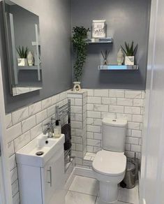 a white toilet sitting next to a sink in a bathroom under a mirror and shelf