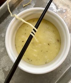 two black chopsticks sticking out of a bowl of soup