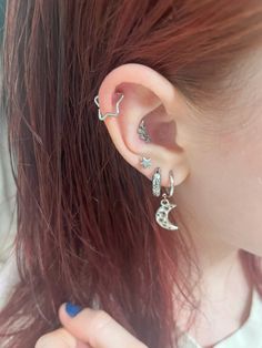 a woman with red hair wearing ear piercings and an earring on her left side