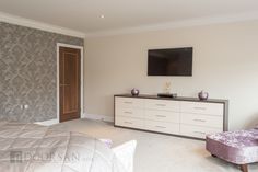 a bedroom with a large bed, dresser and television on the wall in it's corner