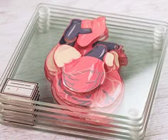 a close up of a heart shaped object in a glass container on a wooden table