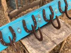 there are several horseshoes hanging from the hooks on this blue board with brown leather handles