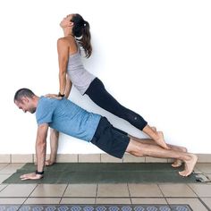 a man and woman are doing yoga on the floor with their hands in each other's pockets