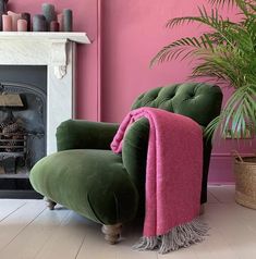 a green chair with a pink blanket on it in front of a fireplace