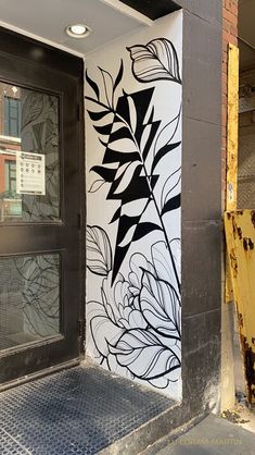 a black and white painting on the side of a building next to a yellow door