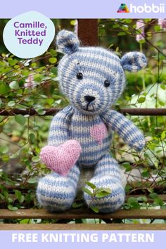 a knitted teddy bear sitting on top of a tree branch with a pink heart