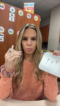 a woman sitting at a desk holding up a piece of paper with the word i love you written on it