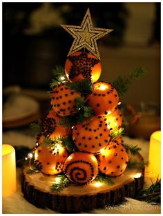 a christmas tree made out of oranges and pine cones is lit by candles on the table