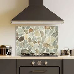 a stove top oven sitting inside of a kitchen next to a wall covered in rocks