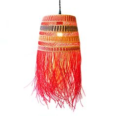 a red and yellow lamp hanging from a ceiling fixture with fringes on the bottom