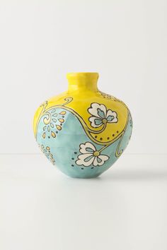 a yellow and blue vase sitting on top of a white table